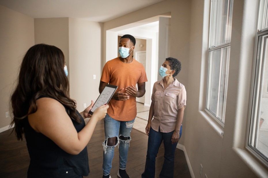 A real estate agent shows a young couple around an empty home for sale.