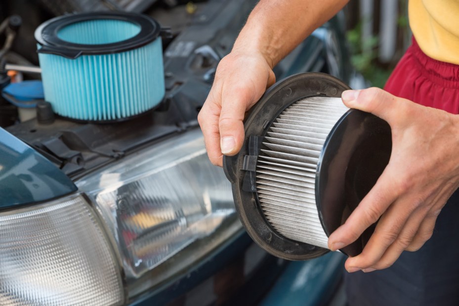 A driver removes the dirty engine air filter from the car.