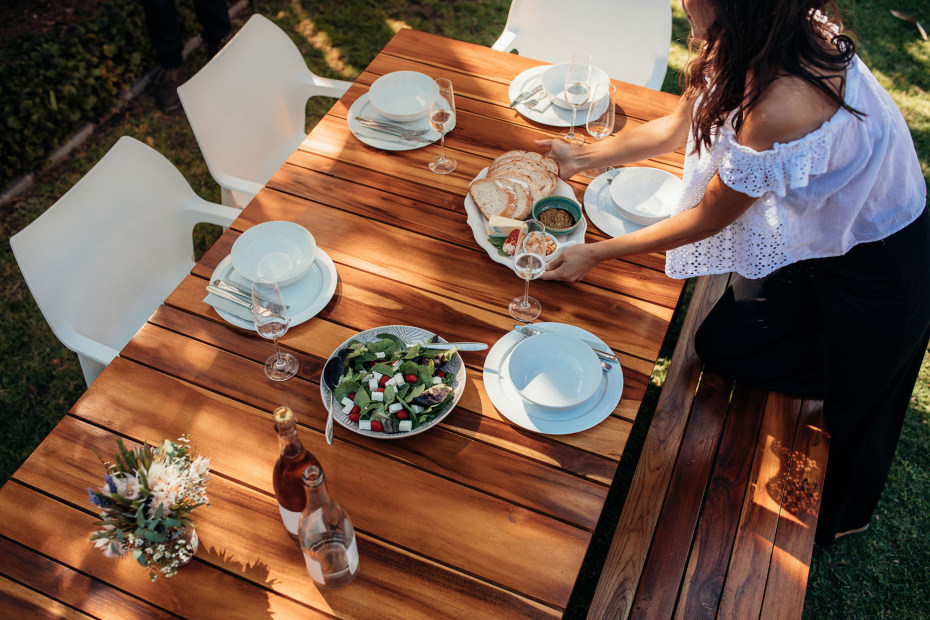 A woman sets an outdoor dinning table for dinner.