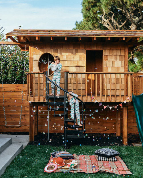 Two young kids play on a Yardzen backyard fort.