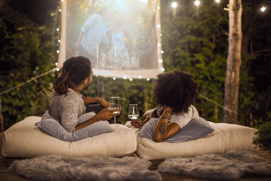 A couple watch a home movie in their backyard.