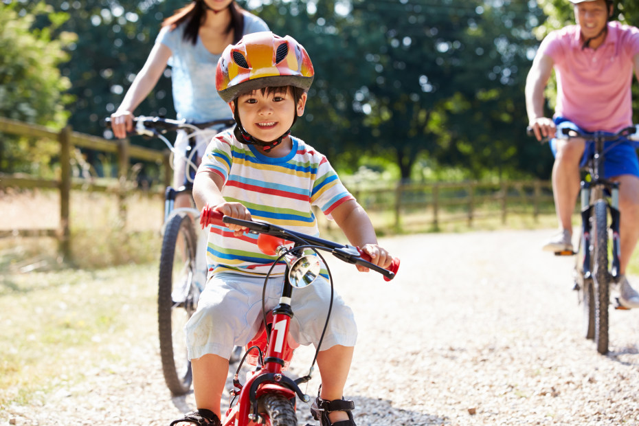 A little boy rides his bike with his parents.