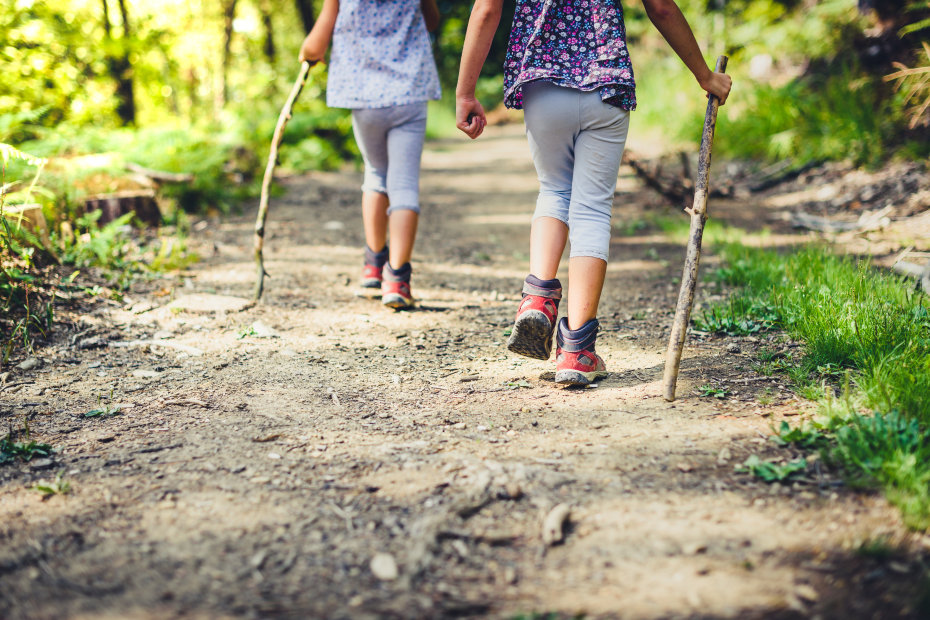 Two young girls hike with their walking sticks.
