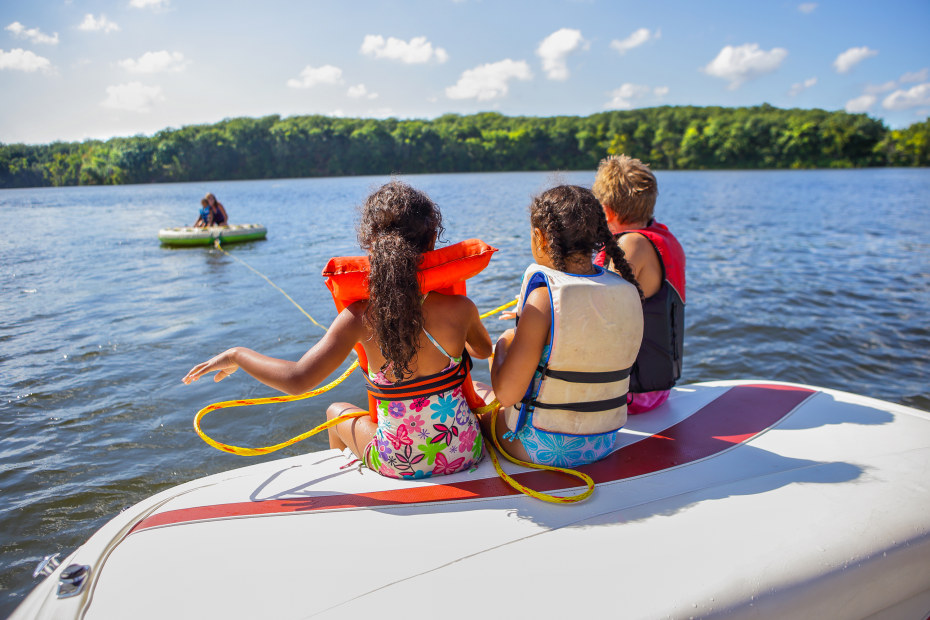 A group of kids prepare to go inner tubing behind a boat.