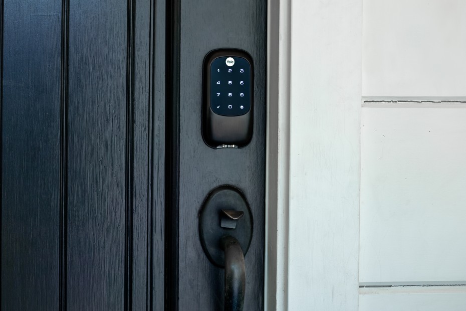 Black smart lock on a dark front door.