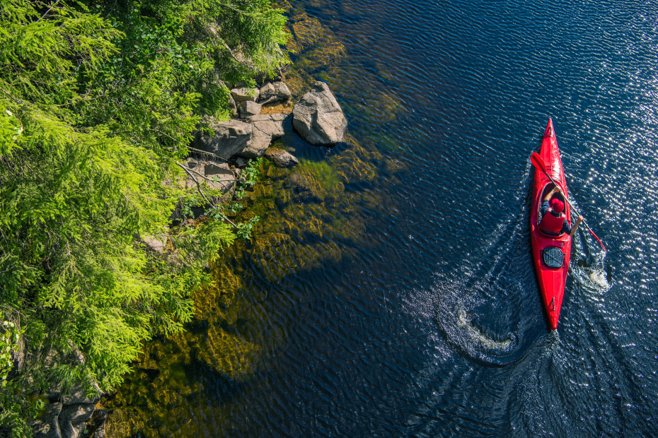 A kayaker paddles along the shoreline.