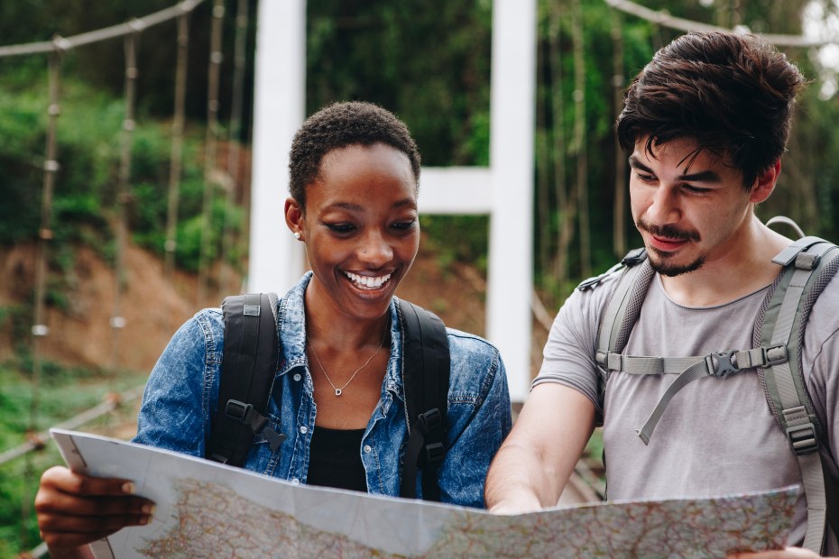 A couple look a trail map after crossing a foot bridge.