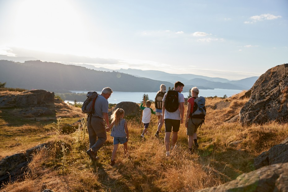 Grandparents, parents, and kids hike together overlooking a bay.