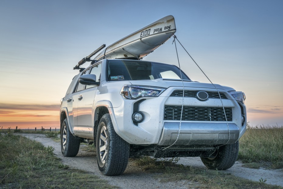 An SUV with a canoe tied to the roof rack.