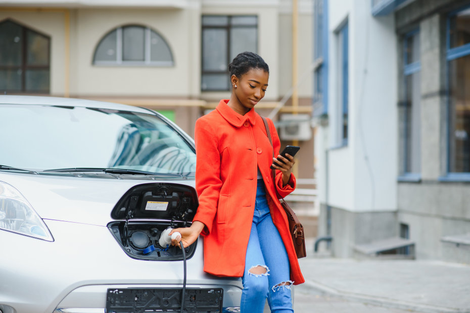 A woman charges her electric car in the cold.