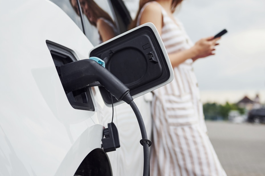 A woman checks on her car's charging on her cell phone.