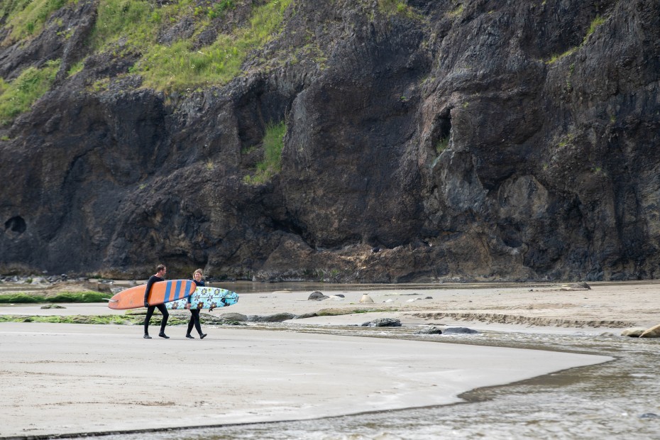 Two surfers walk on Agate Beach in Newport, Oregon.