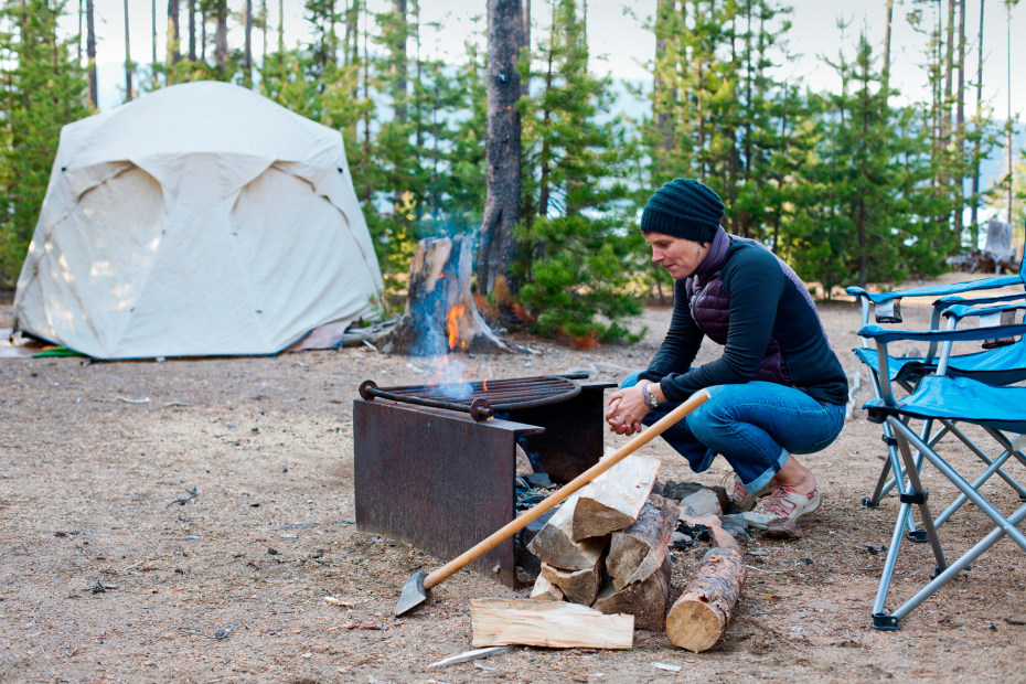 A woman tends a campfire.