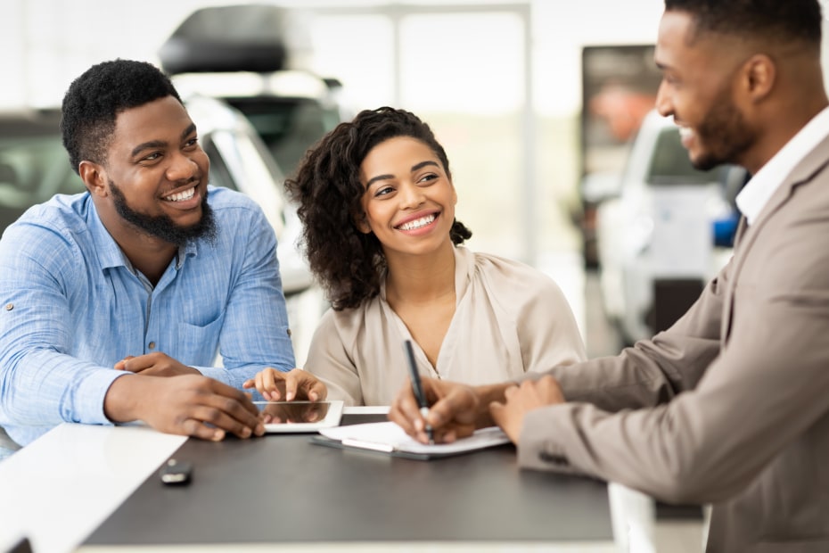 A couple negotiate with a car sales person.