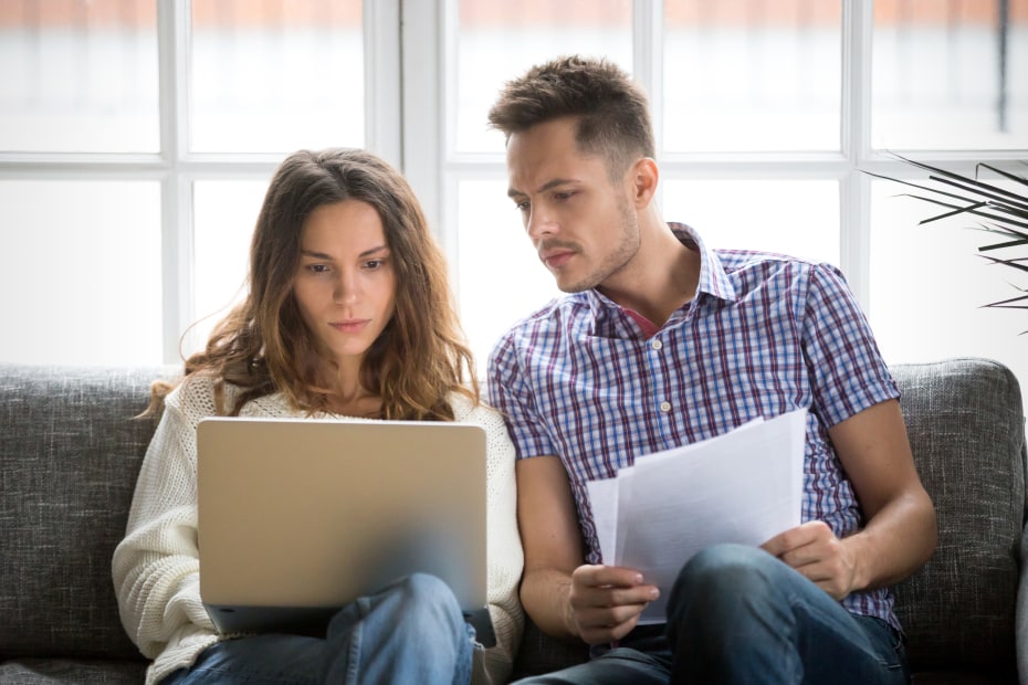 A couple clean out emails on their couch.