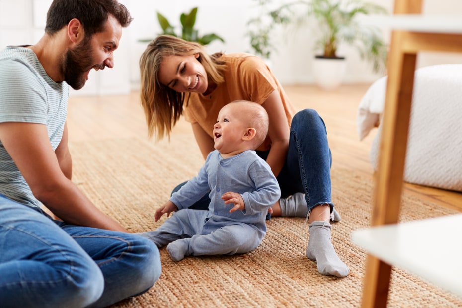 Parents play with their baby on the floor.