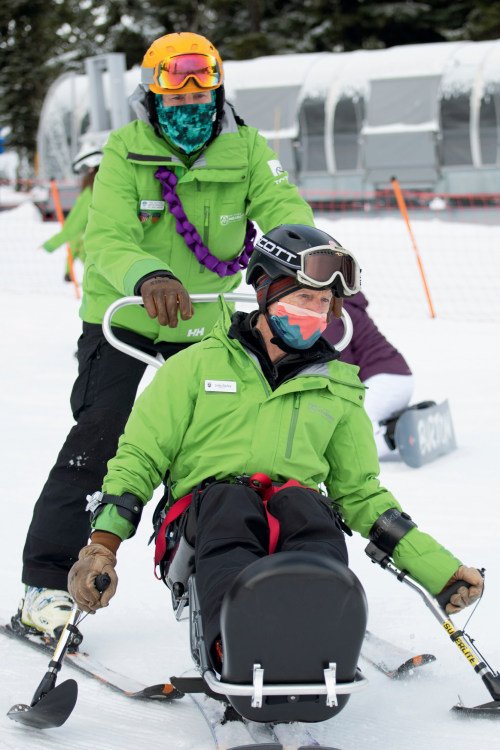 An adaptive skier on a downhill run with a guide.