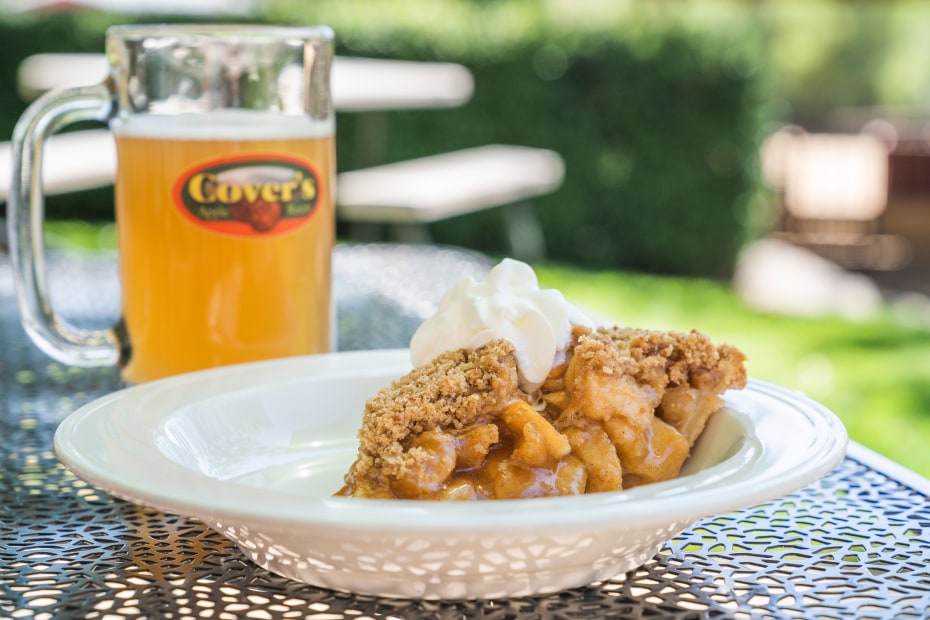 A glass of sparkling apple cider and fresh made Dutch apple pie on a table at Covers Apple Ranch.