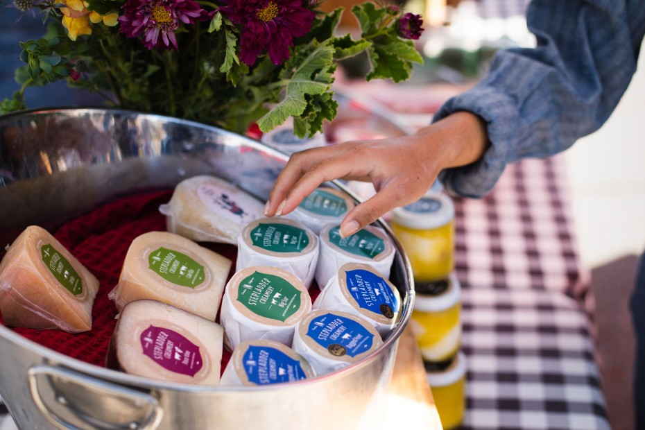 A woman browses cheese from Stepladder Creamery at Cambria Farmers Market.