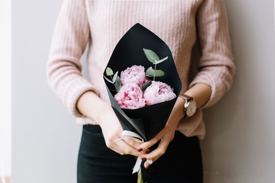 A woman holds a bouquet of pink flowers.