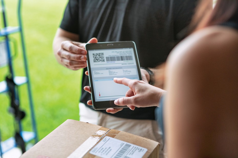 A woman signs for a package delivery.