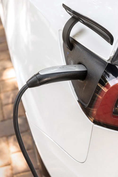 An EV charger pulugged into a Tesla Model 3 charging port.