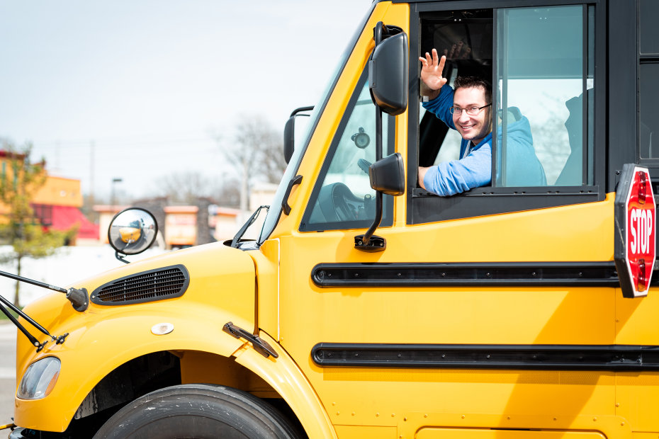 Bus driver waves out the window.