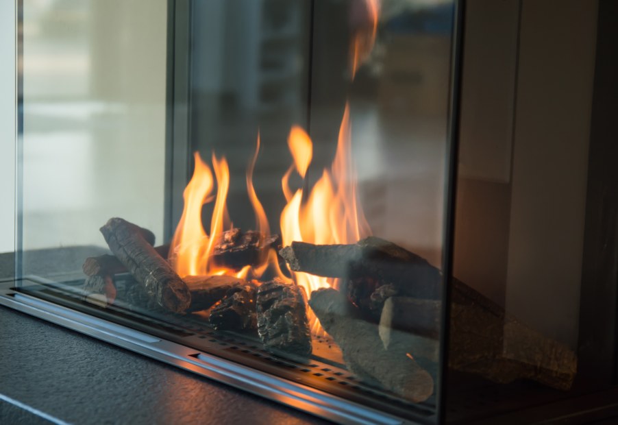 A lit gas fireplace insert with a glass front.