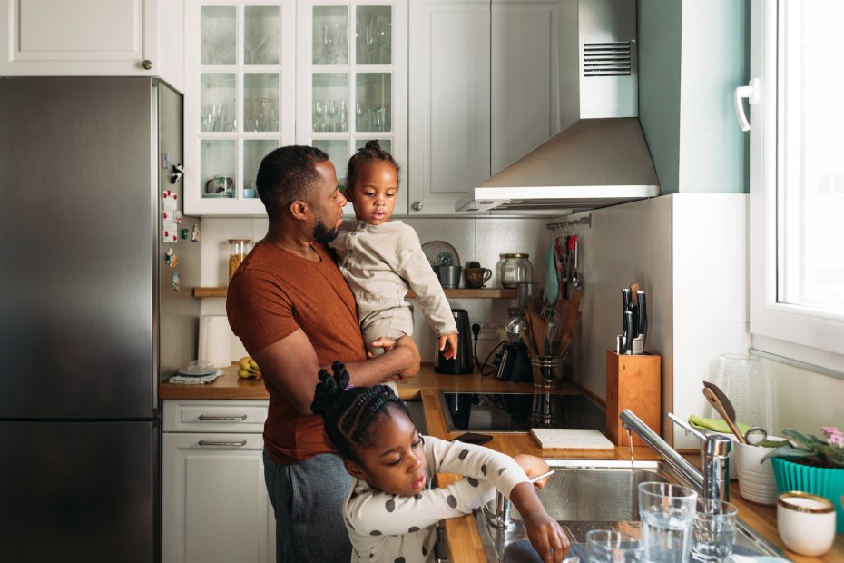 A dad and his children do the dishes together.