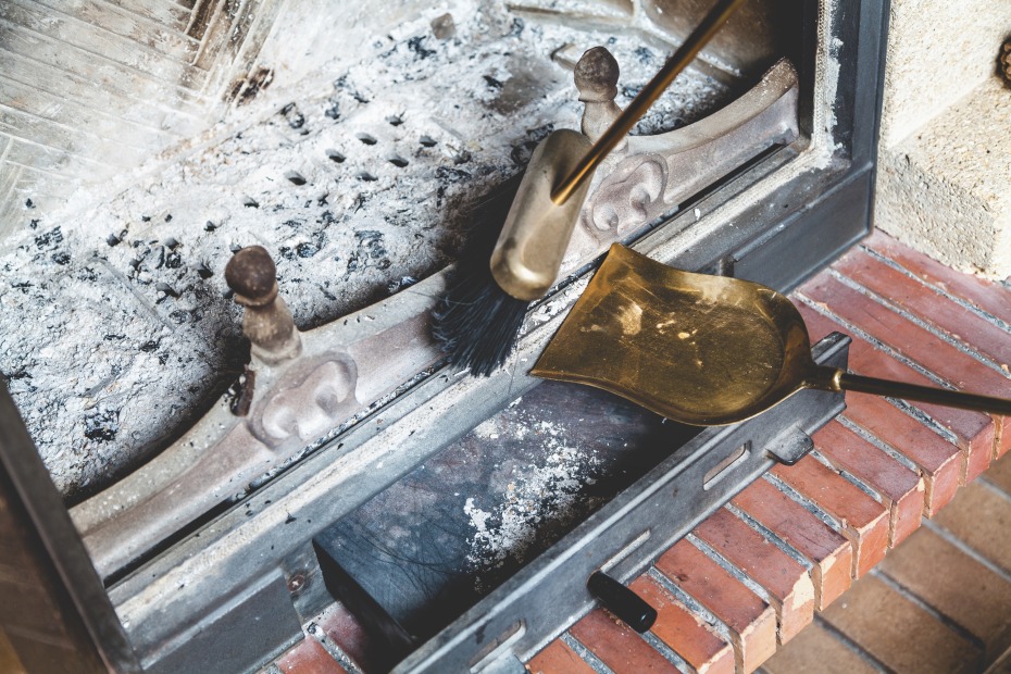 A person sweeps out the ash in the bottom of their fireplace.