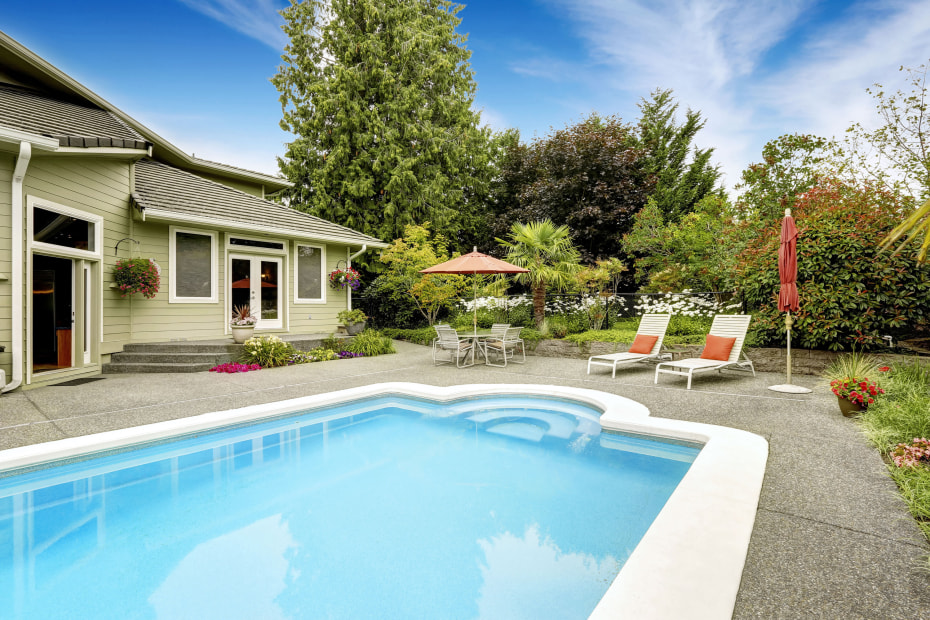 Backyard with a turquoise swimming pool and patio area.