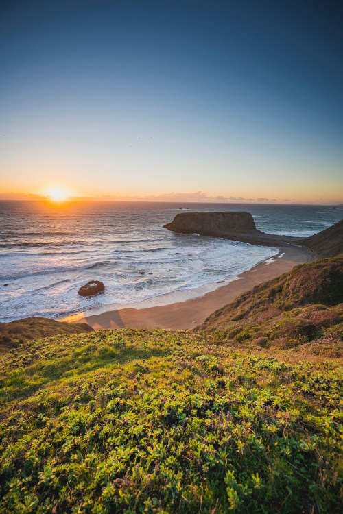 The sun sets behind white waves in Goat Rock State Park.