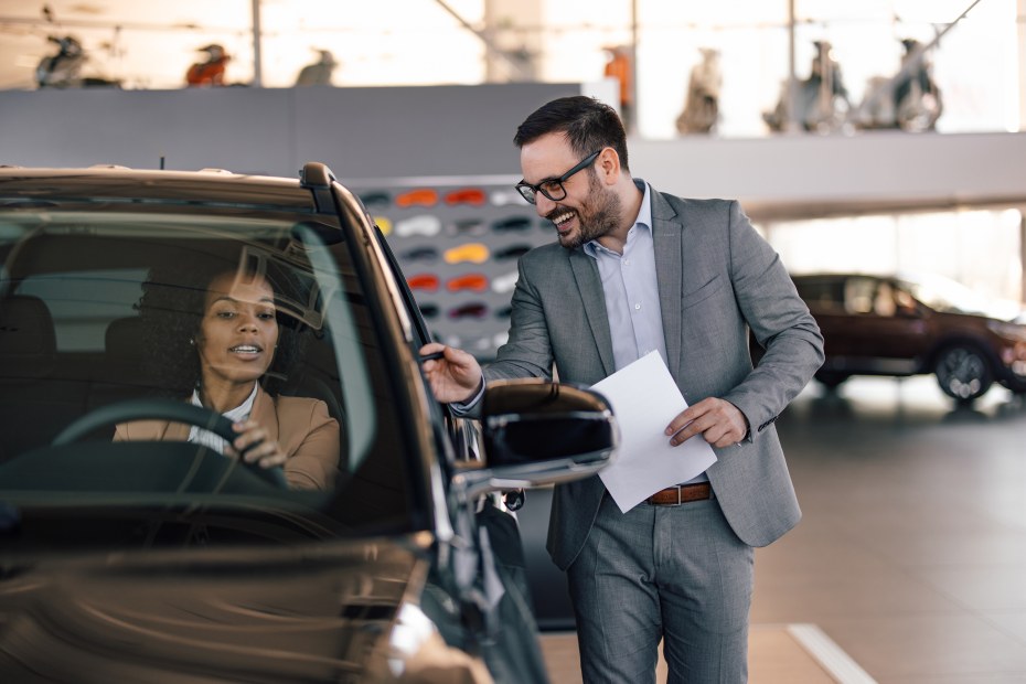 A sales person explains the features on an SUV to a prospective buyer.