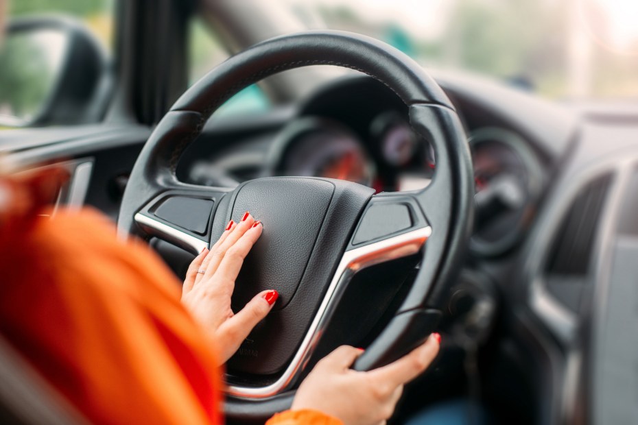 A woman honks the horn on her car.