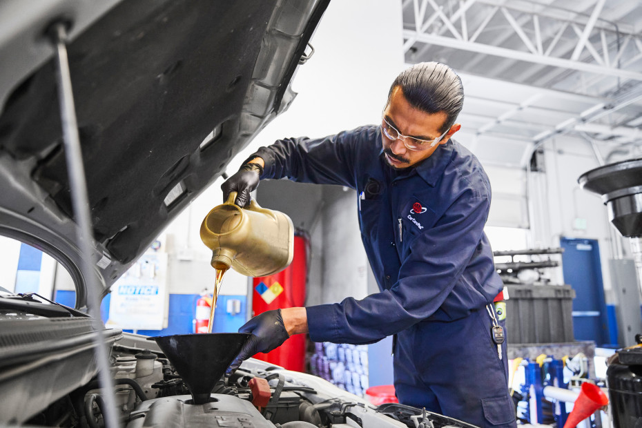 AAA Auto Repair mechanic adds new oil to a car's engine.
