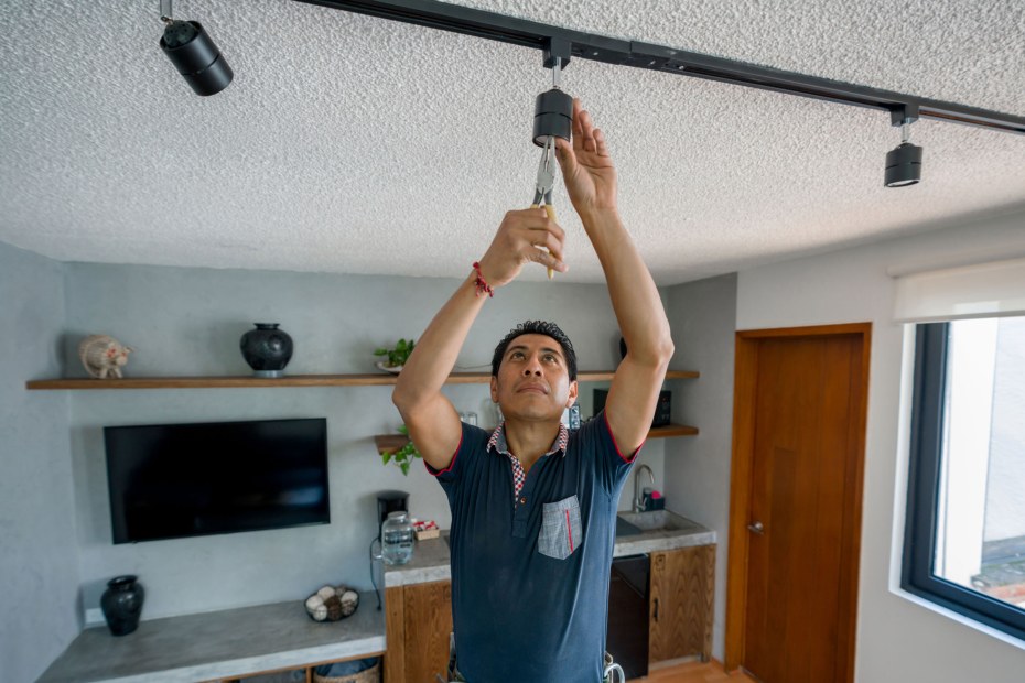 An electrician installs track lighting.