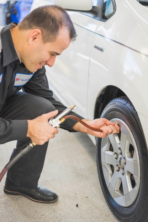 AAA Auto Repair mechanic inflates a Toyota Prius tire.