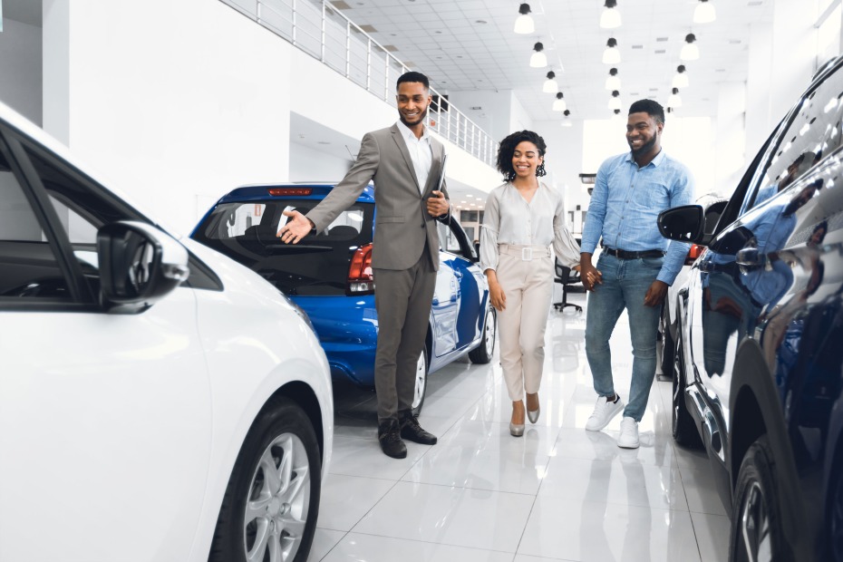 A couple walk through a car dealership with a sales person.