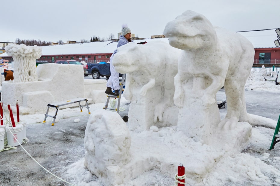 A woman sculps snow dinosaurs at Fur Rendezvous in Anchorage, Alaska.