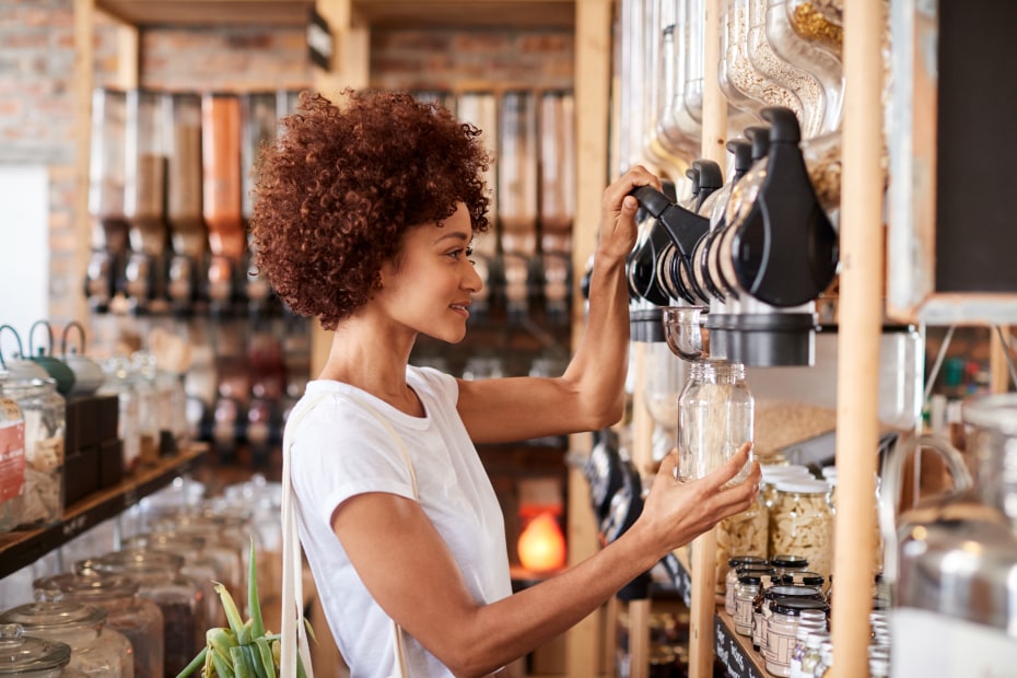 A woman fills a glass jar with bulk snacks.