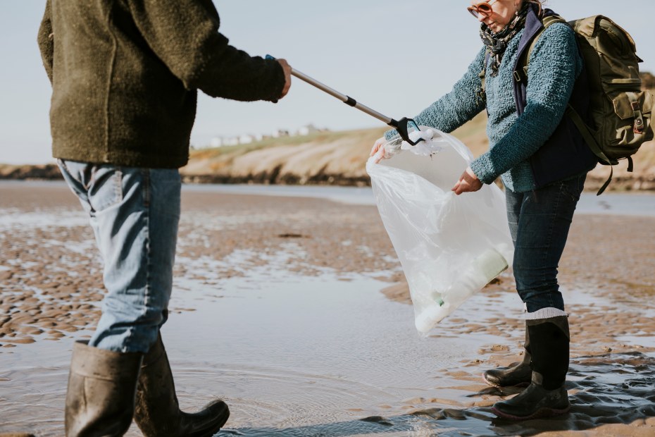 Travelers clean up trash on a beach.