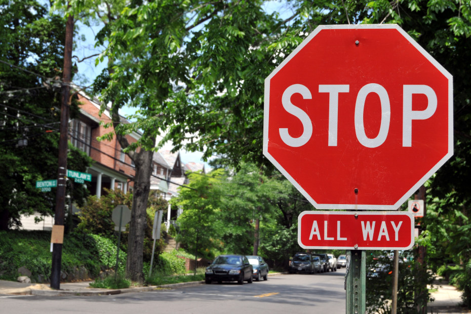 A stop sign on a tree-lined street.