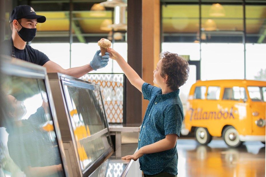A worker hands a child an ice cream cone inside the Tillamook creamery.