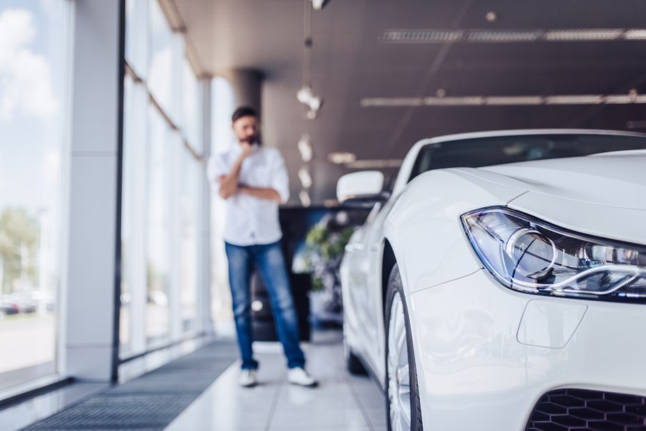 a man at a car dealership looks at a white car, picture