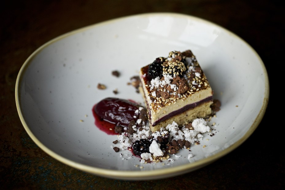 artful dessert, resembling cheesecake or tiramisu, with blackberry sauce, cocoa, coconut, sesame, on a stoneware plate at Le Pigeon in Portland, OR, image