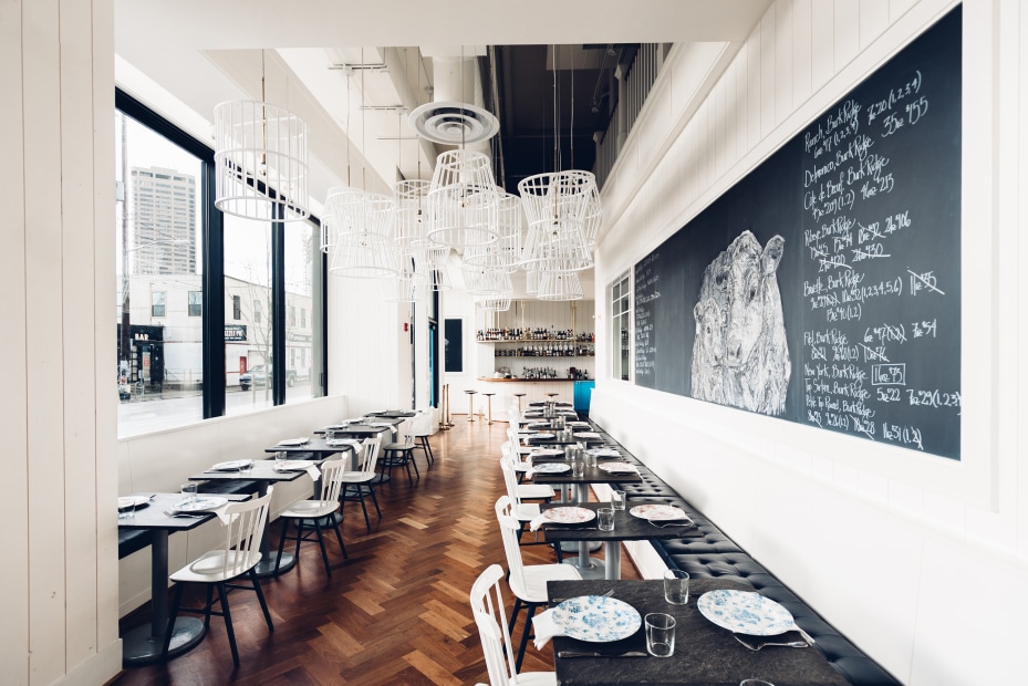 Bateau's bright, light-filled interior is lined with window side tables and cushioned bench banquette beneath a chalkboard mural menu in Seattle, picture