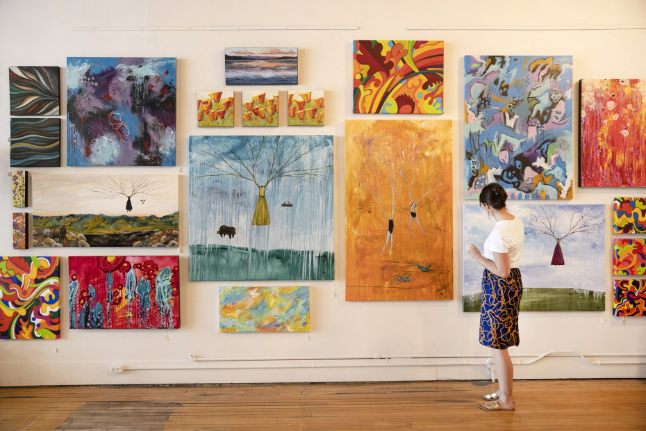 A woman stands in front of a gallery wall at Toucan.