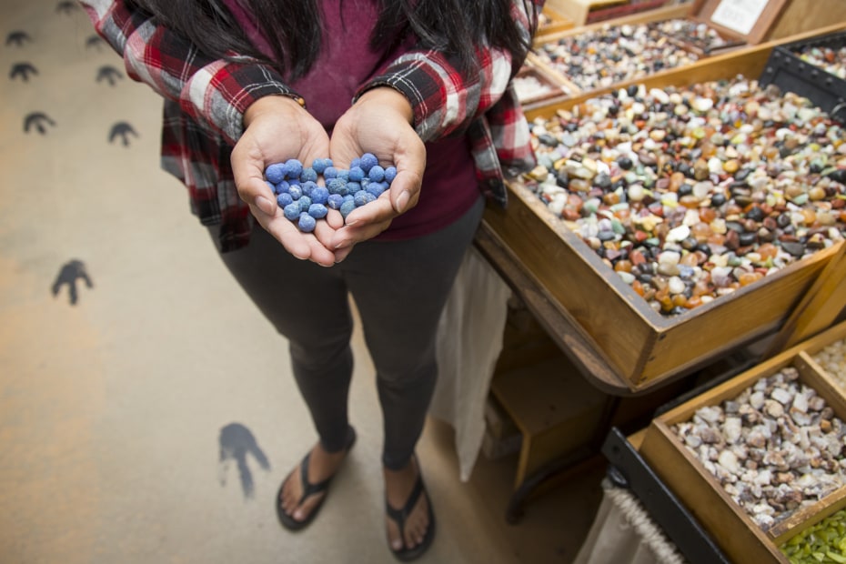 a woman holds blue pebbles in the Moab Rock Shop.