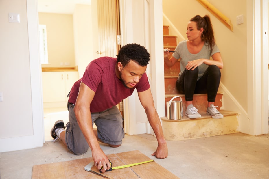 couple works on a home improvement project painting and measuring wood