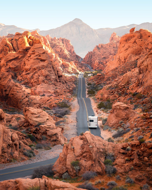 An RV drives on a scenic road between the red rocks in Valley of Fire State Park in Nevada.